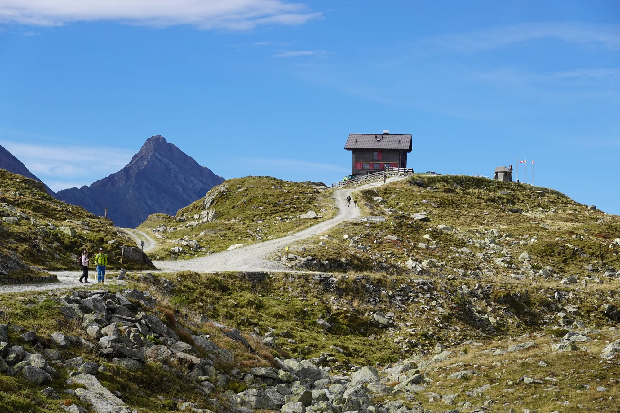 The Pfitscherjochhaus on the pass, a gravel path with hikers in front