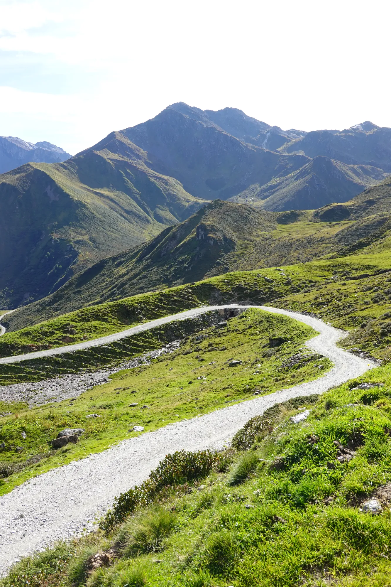 Gravel switchbacks through green alpine meadows on the way to the Geiseljoch