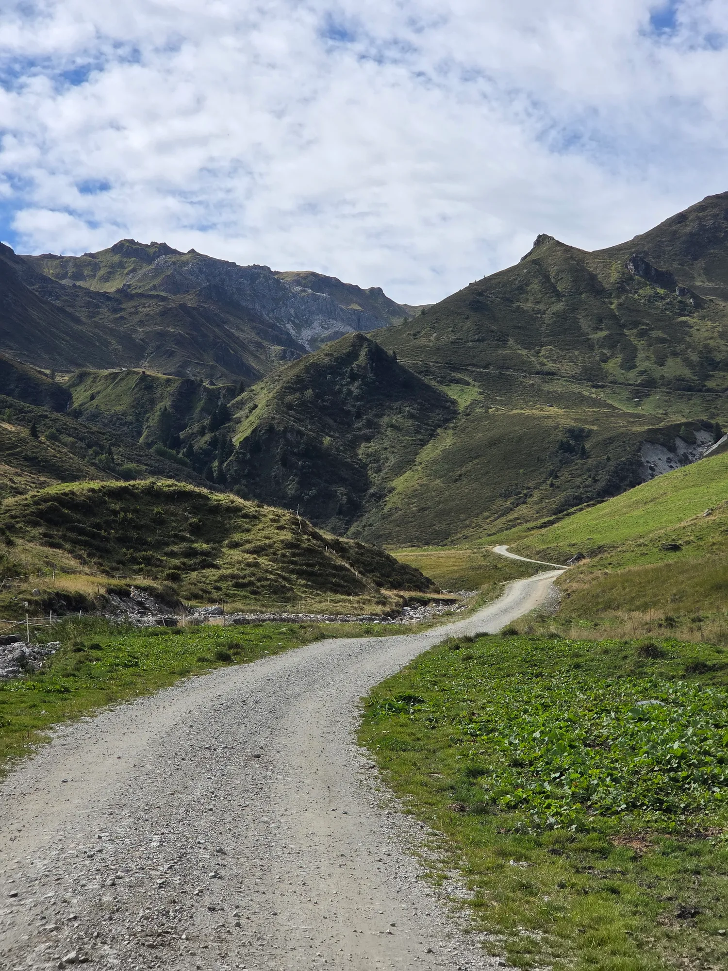 Quiet gravel road between green mountain slopes