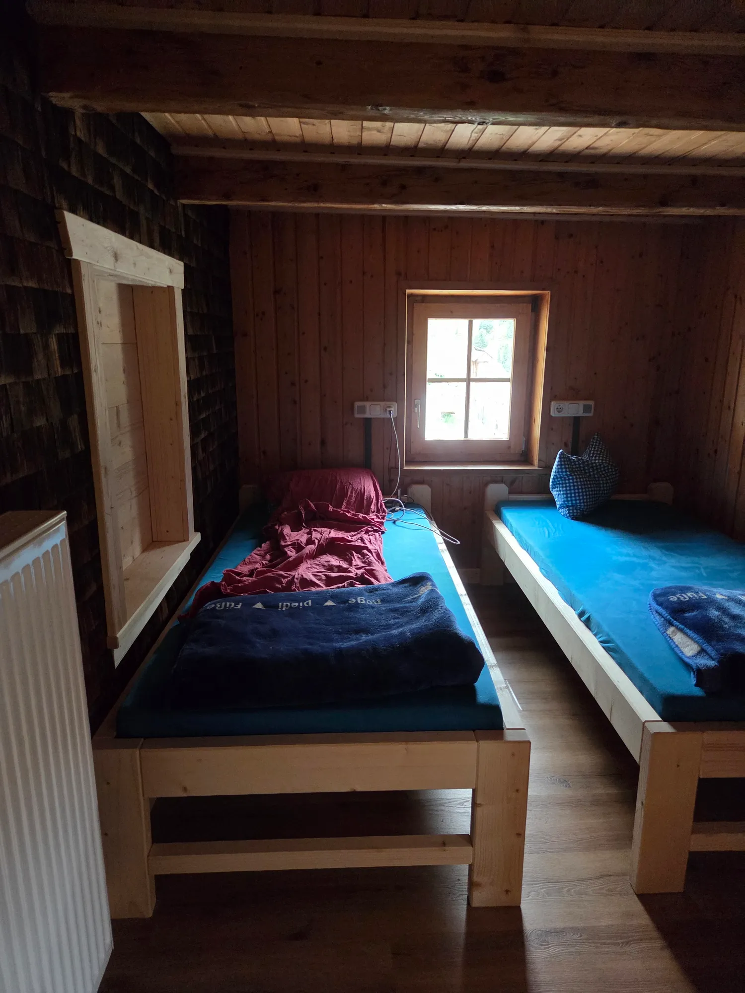 Simple room with two wooden beds at the Weidener Hütte