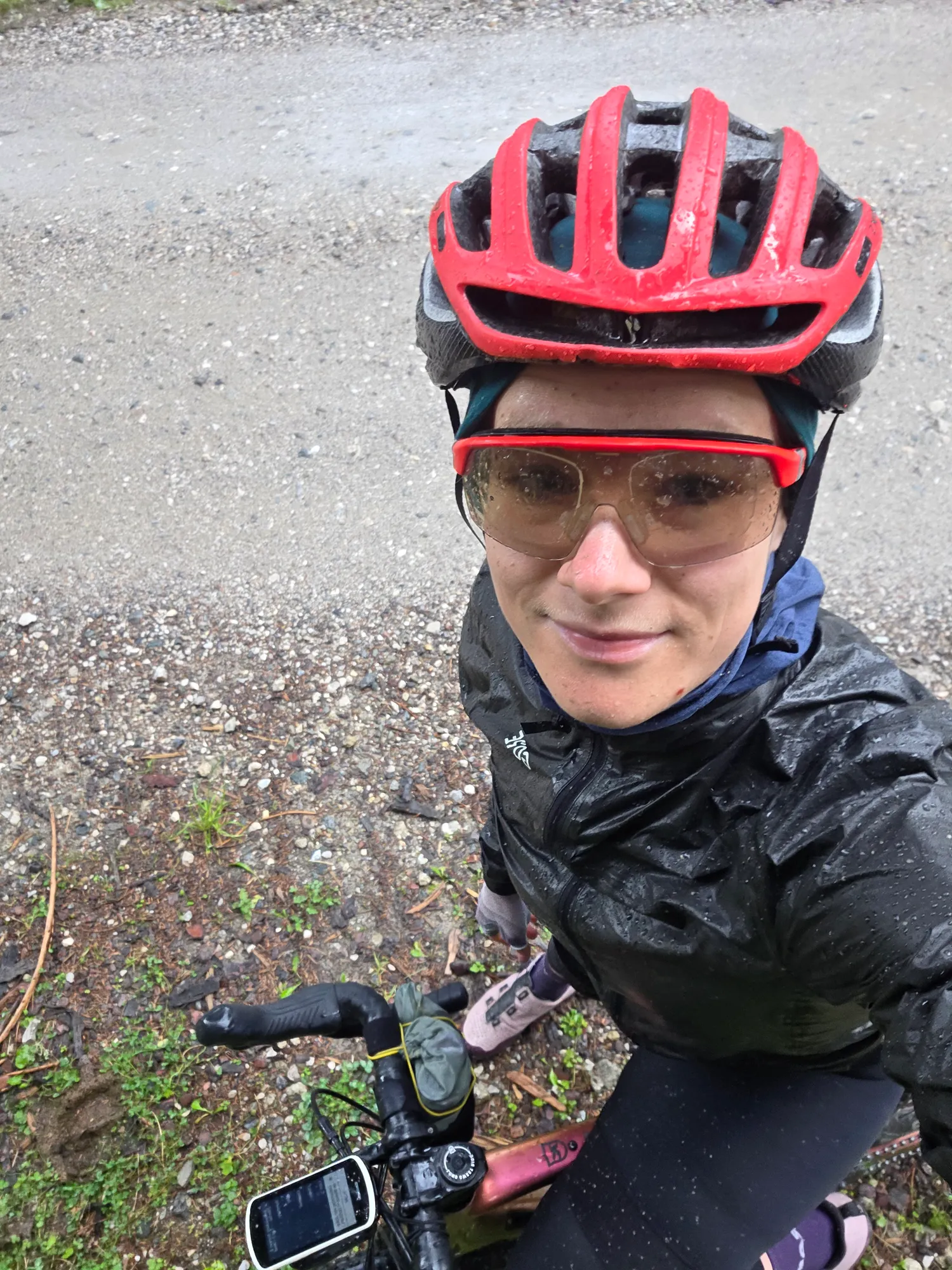 Carla in a rain jacket and red helmet on her gravel bike