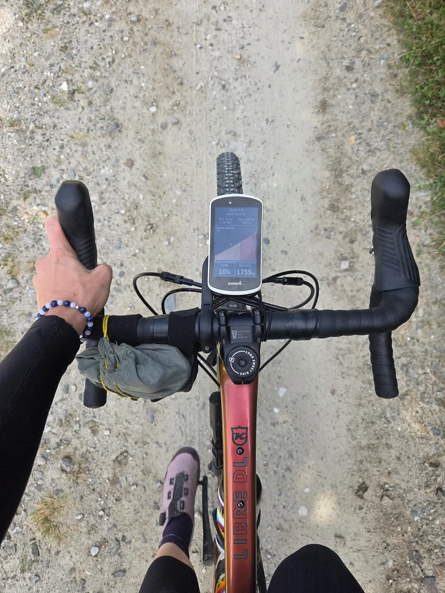 View from the saddle onto handlebars, bike computer and gravel track