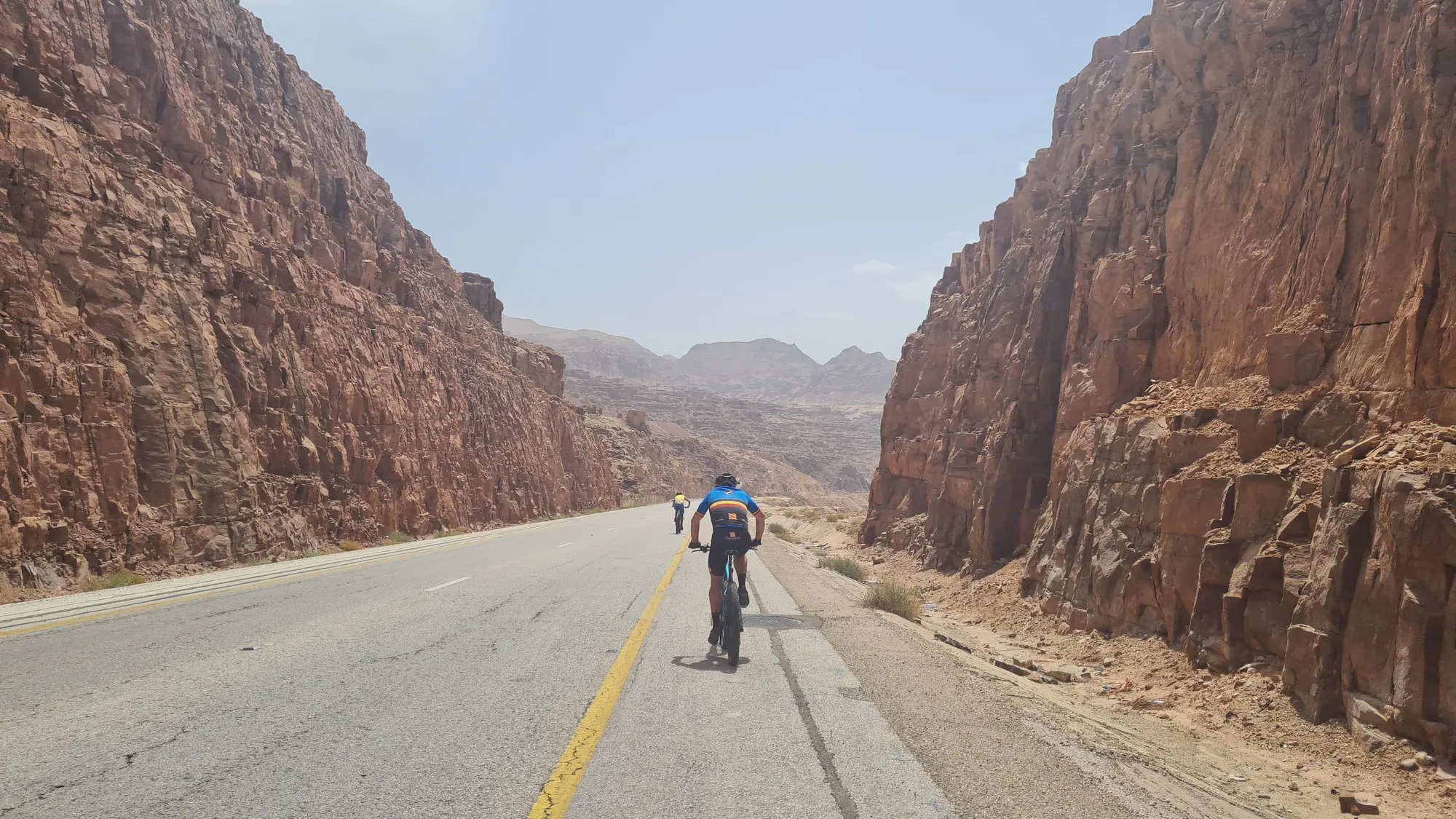 Cyclist on the road through a narrow red canyon