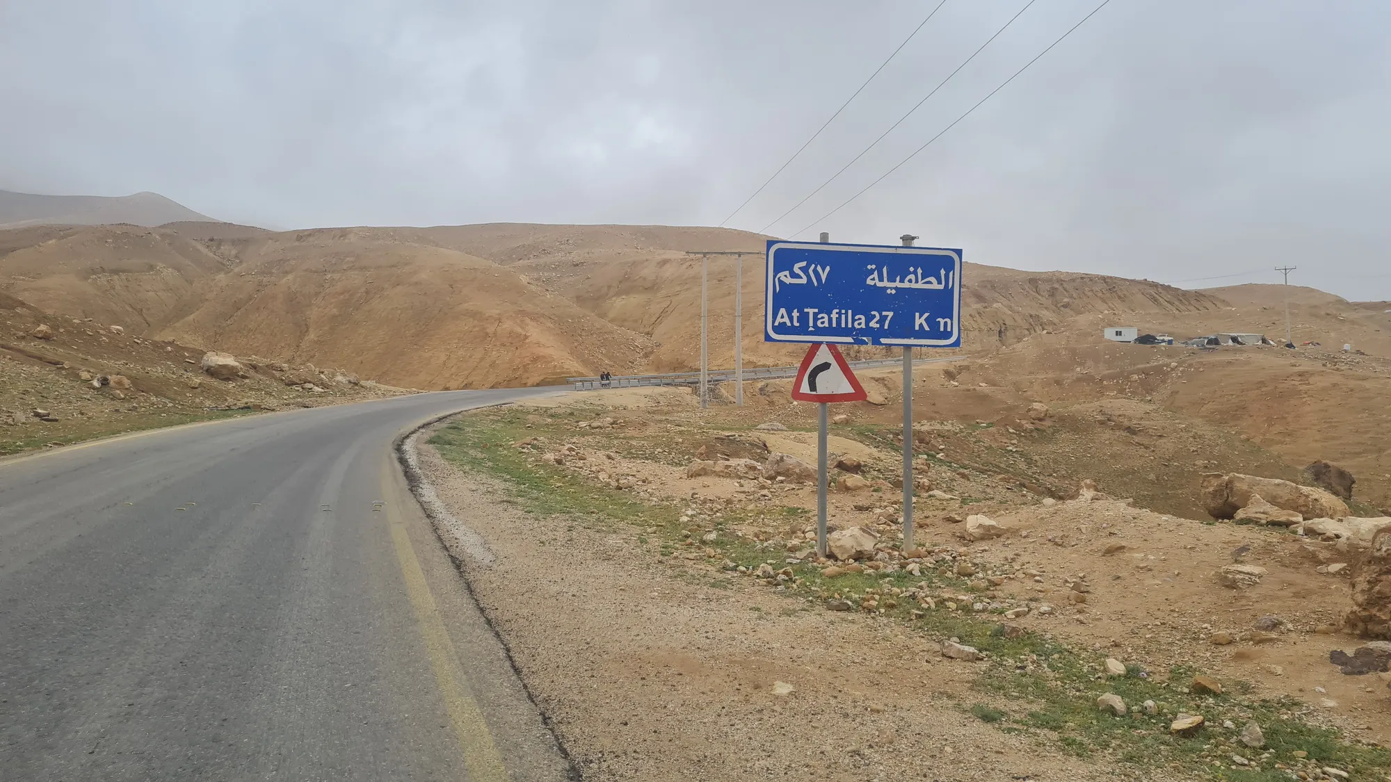 Road sign to Tafila, clouds over the mountains behind