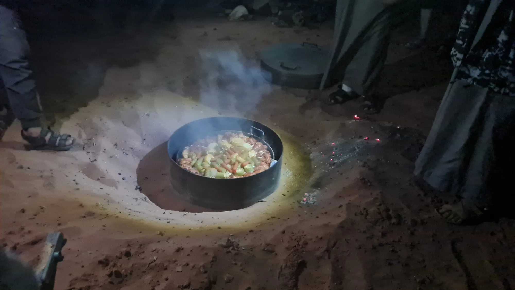 Dinner at the desert camp: a pot in a pit in the sand