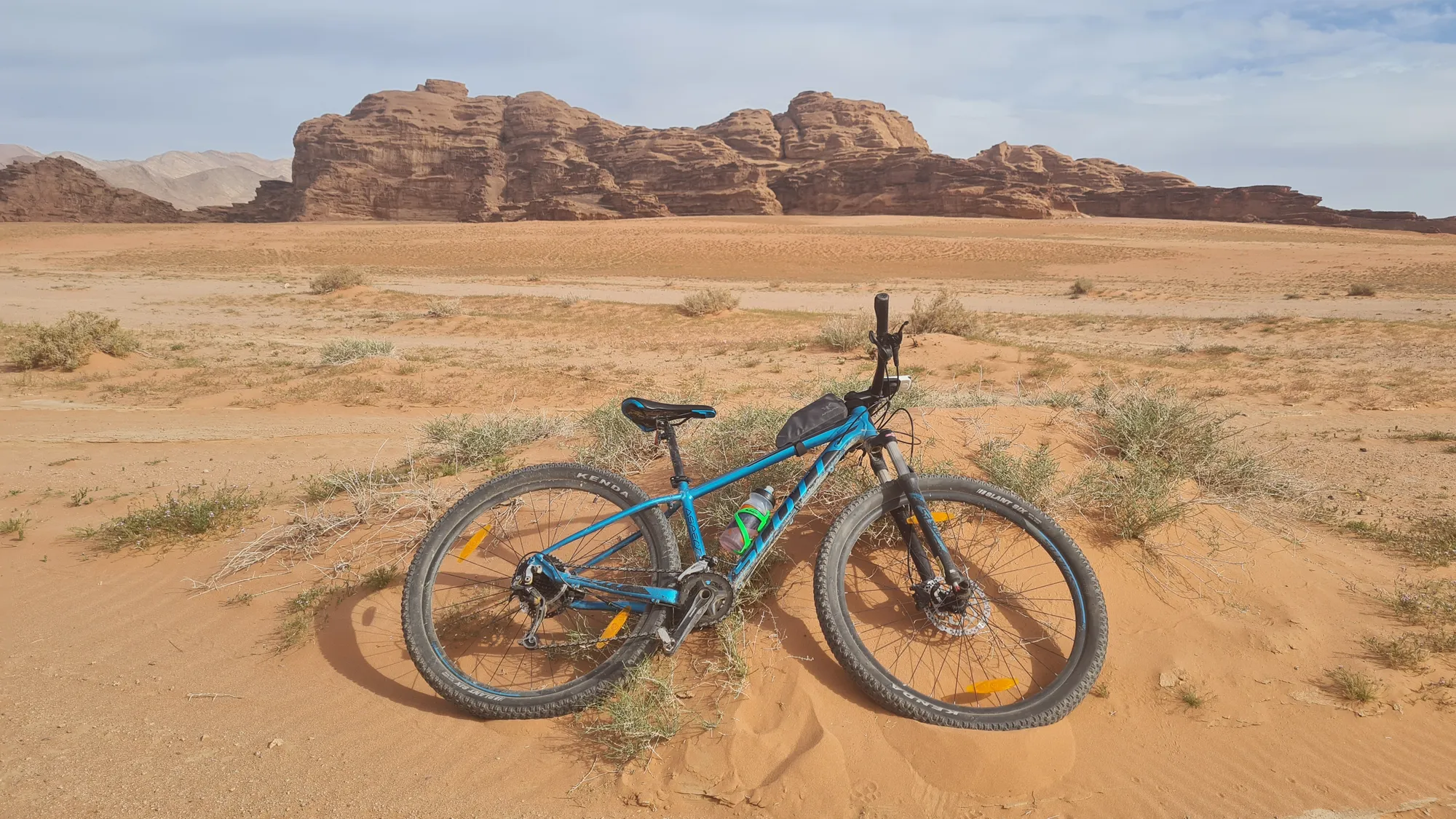 Mountain bike in the red sand in front of the rocks of Wadi Rum