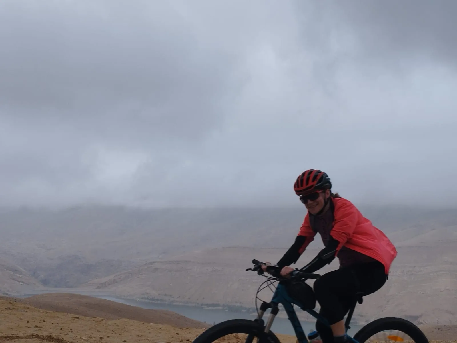 Riding the mountain bike under low clouds, the valley behind