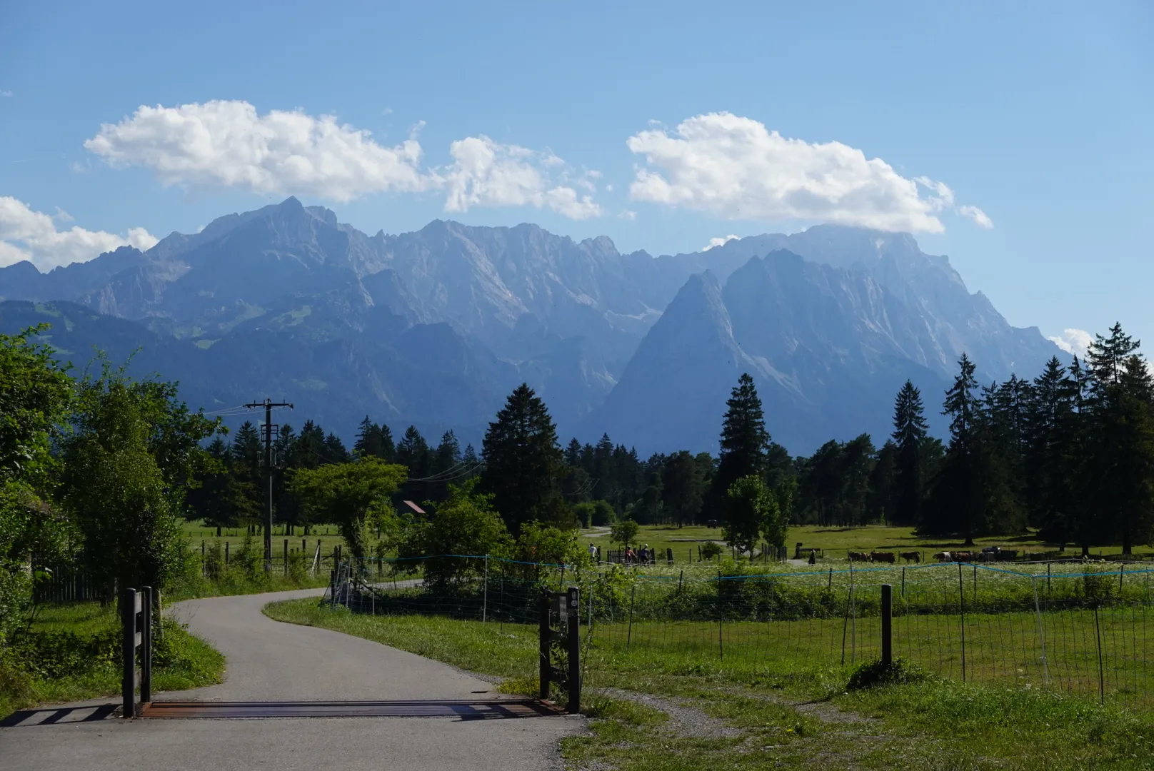 Wide cycle path through green meadows near Murnau, the Wetterstein mountains behind
