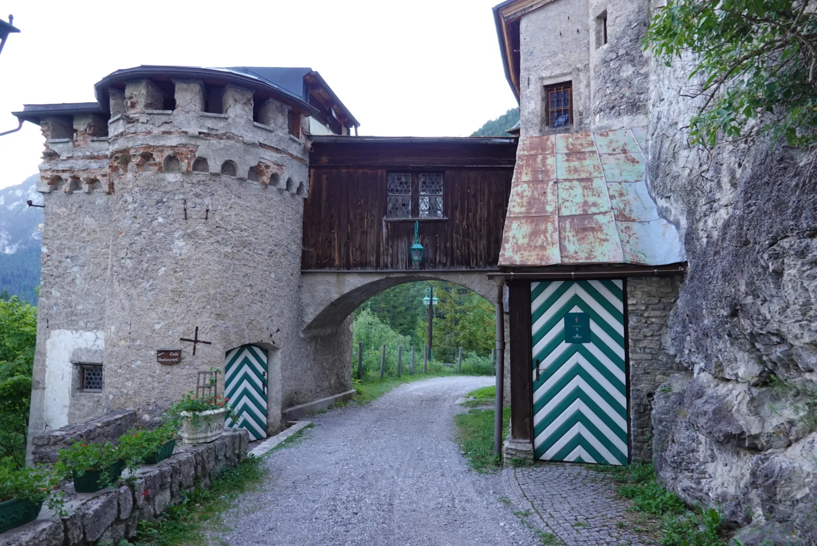 Gravel track through a stone gatehouse with a tower and green-and-white striped doors
