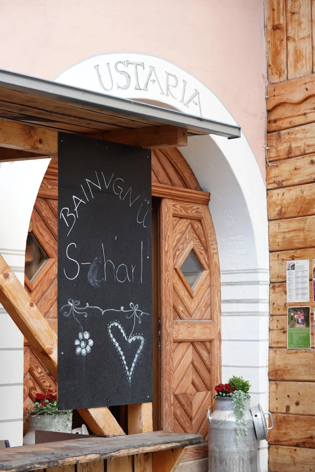 Chalkboard reading "Bainvgnü S-charl" at the entrance of the Ustaria