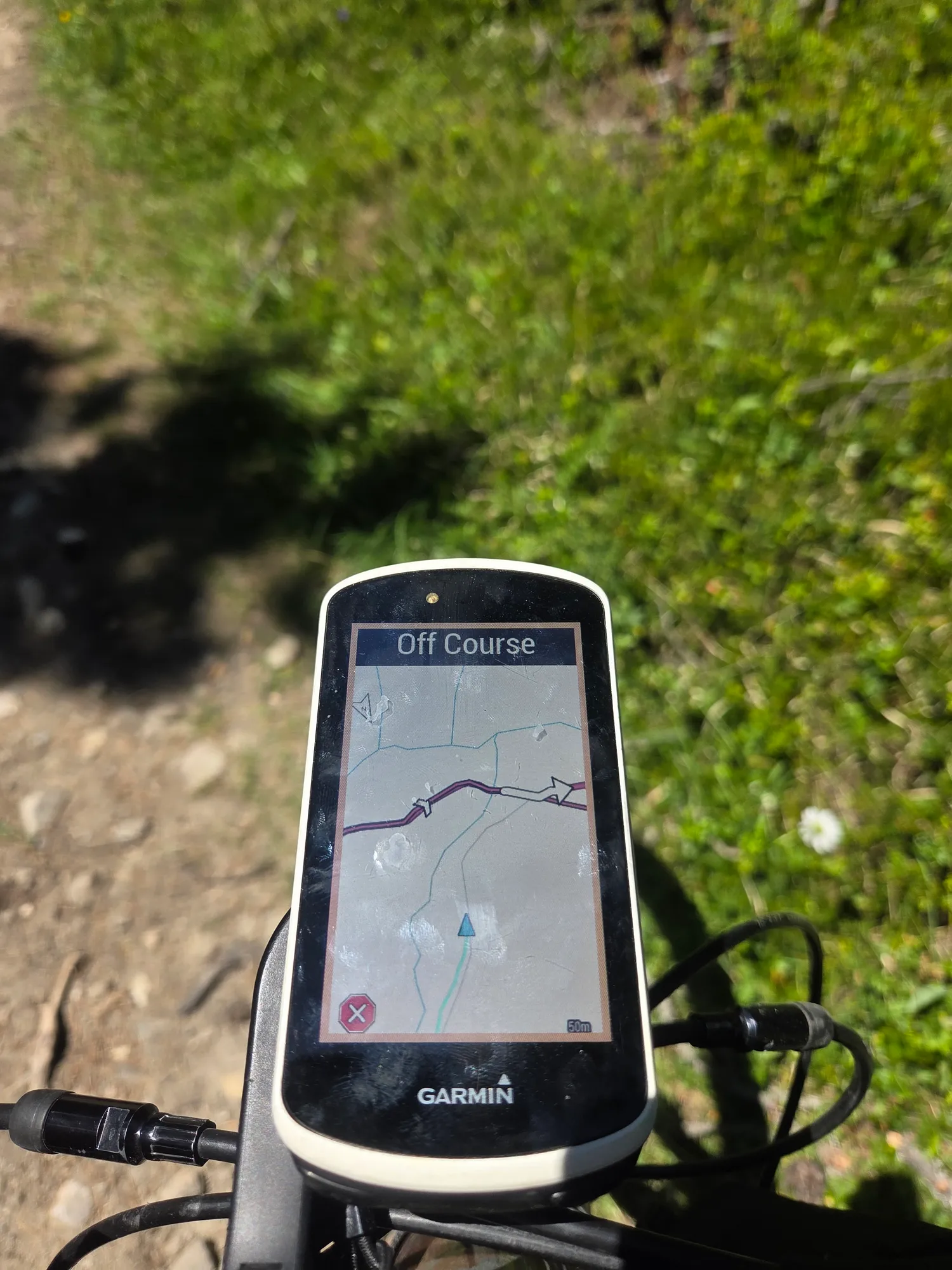 Bike computer showing "Off Course" on a meadow path