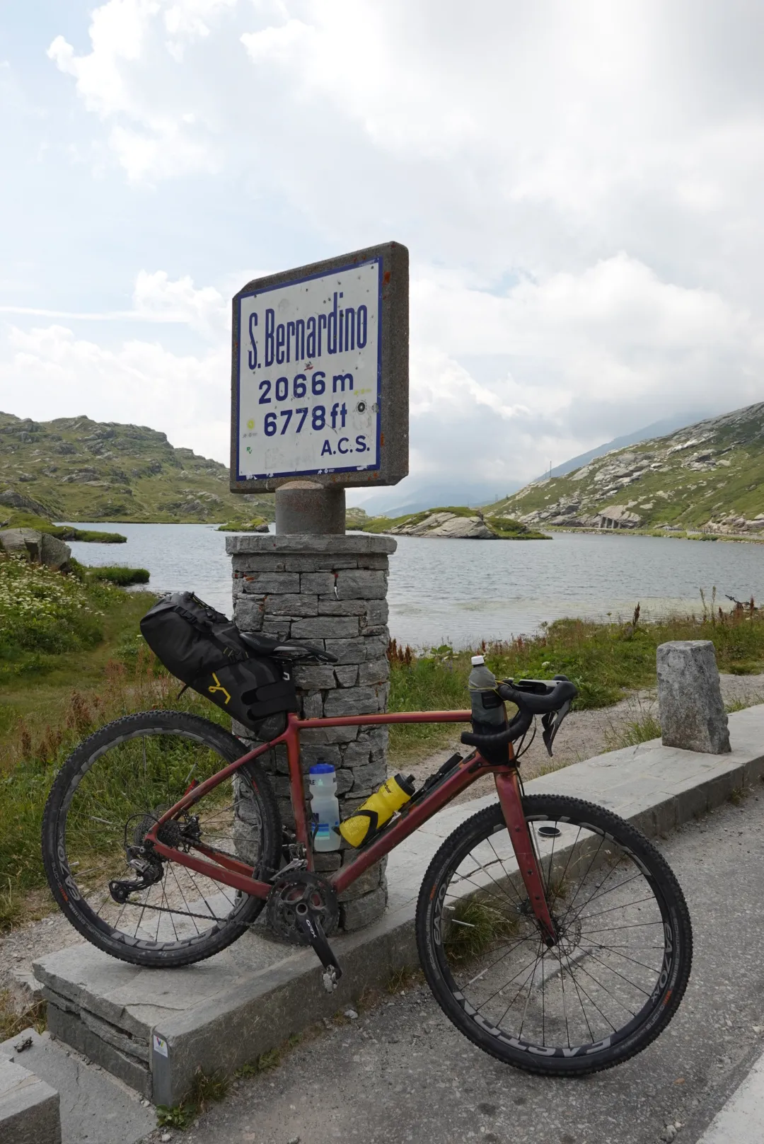 Gravel bike at the San Bernardino pass stone, 2066 m