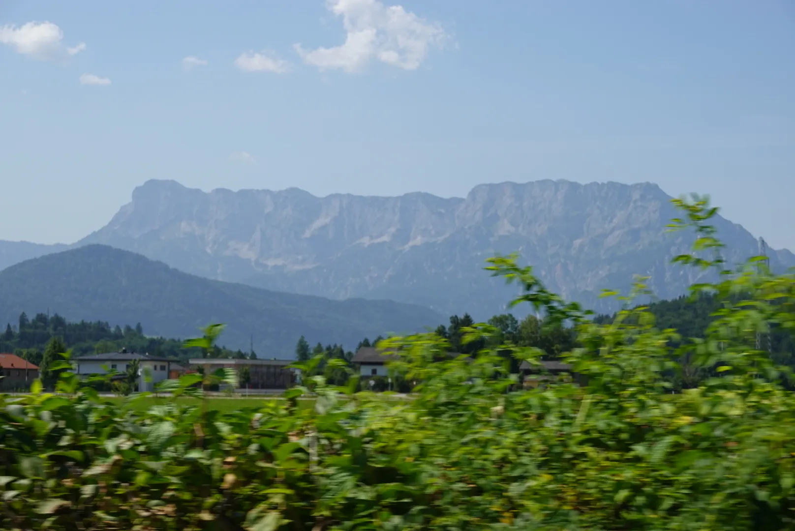 Wide limestone massif above green hedges