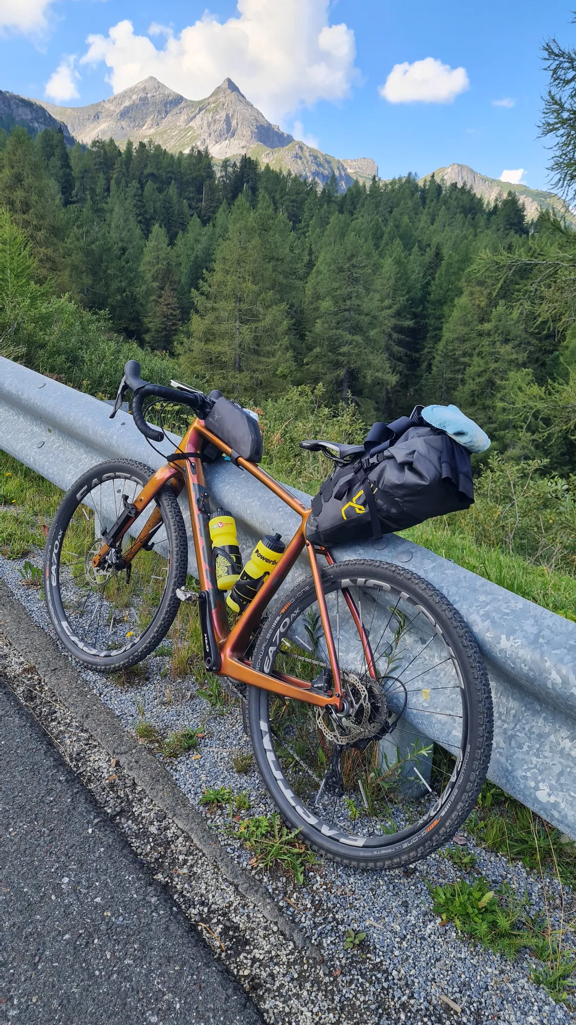 Loaded gravel bike against the crash barrier, a pointed peak behind