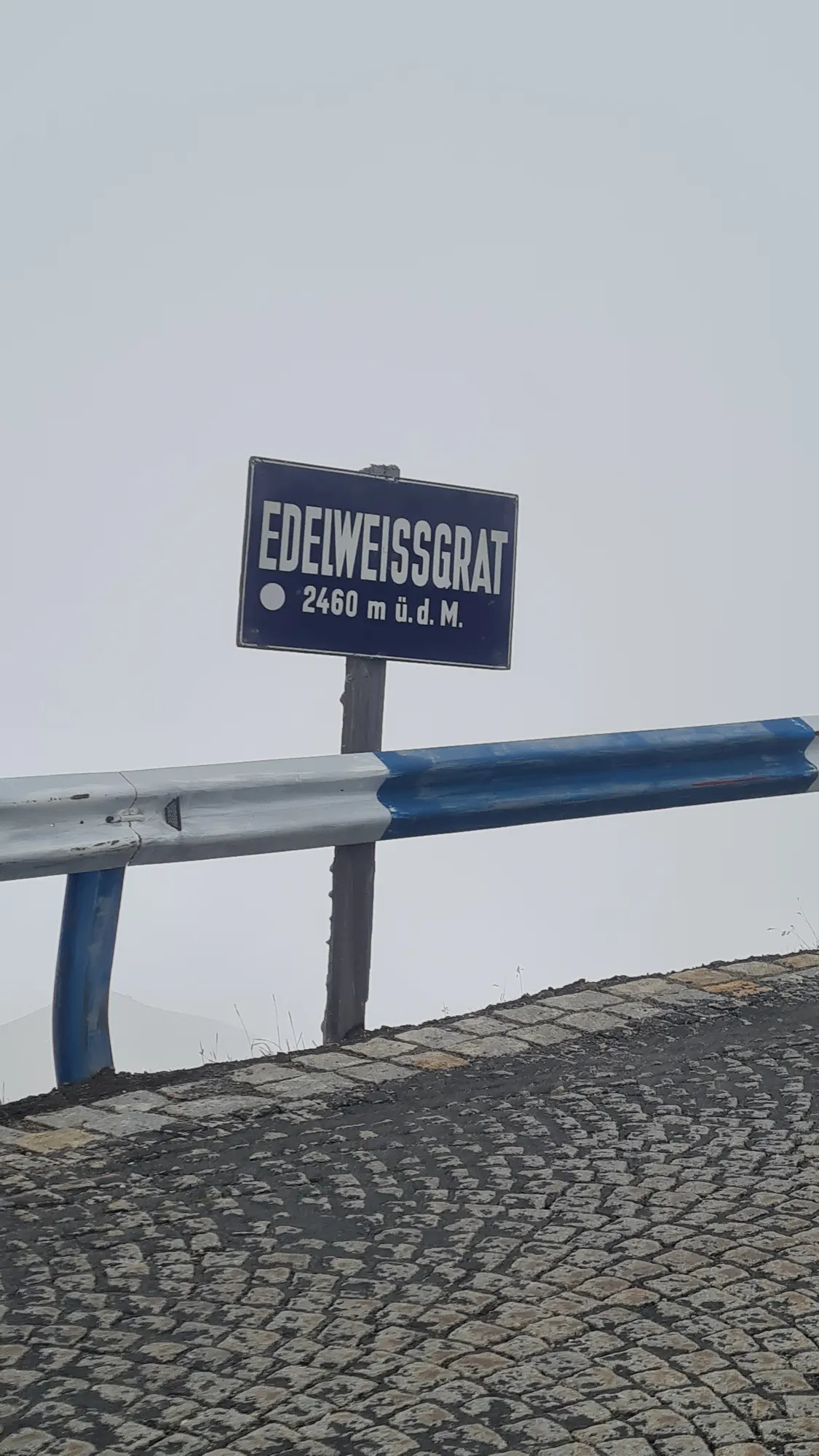 “Edelweissgrat” sign on the cobbled road in the fog