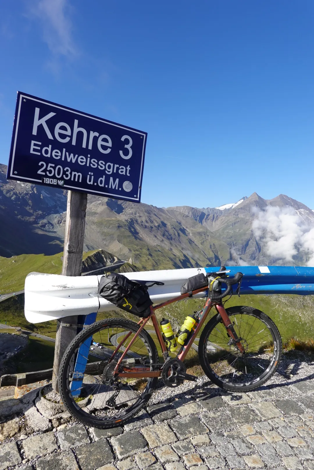 Gravel bike at the sign “Kehre 3 Edelweissgrat, 2503 m”