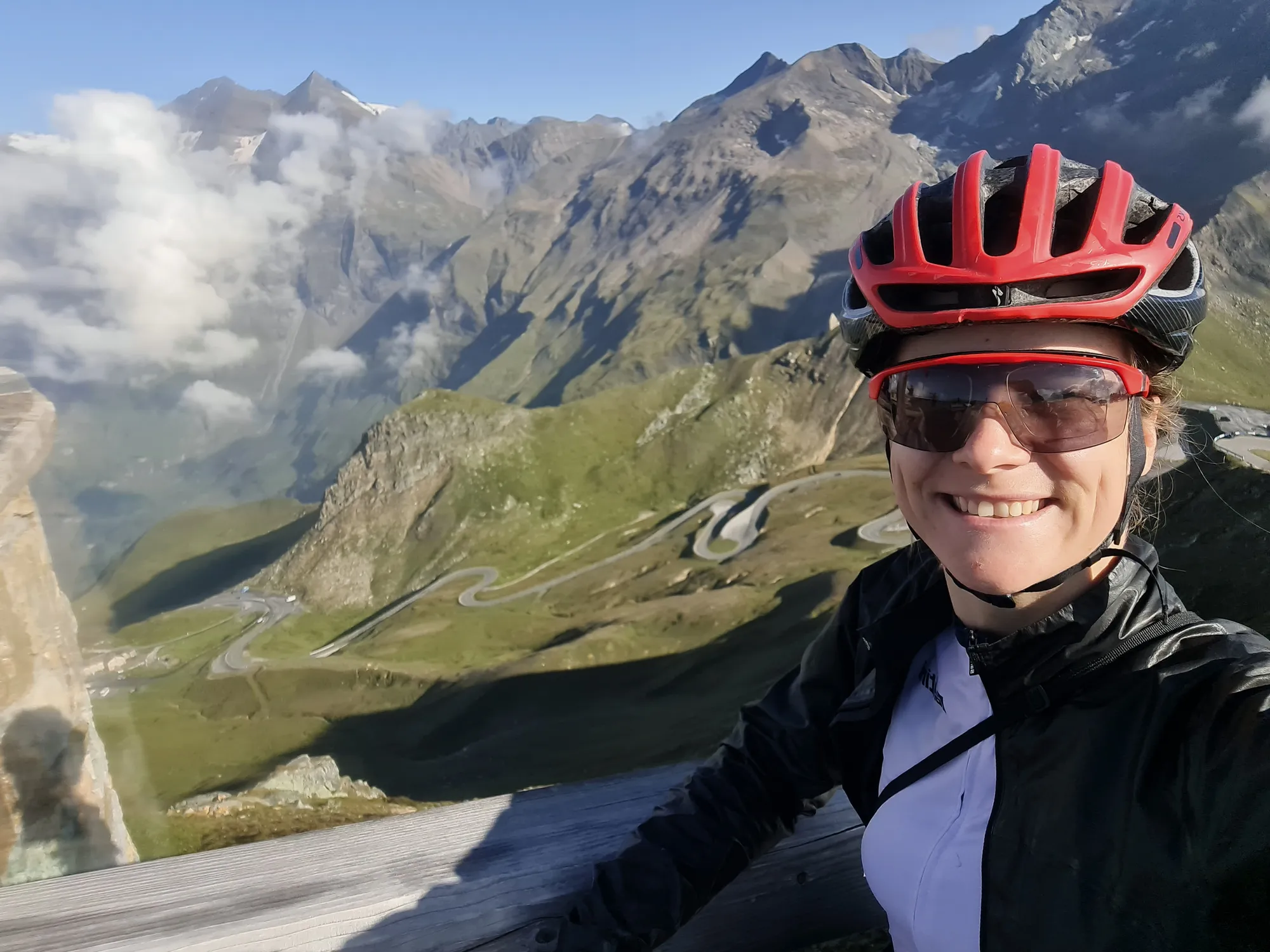 Carla in a red helmet in front of the hairpins of the High Alpine Road