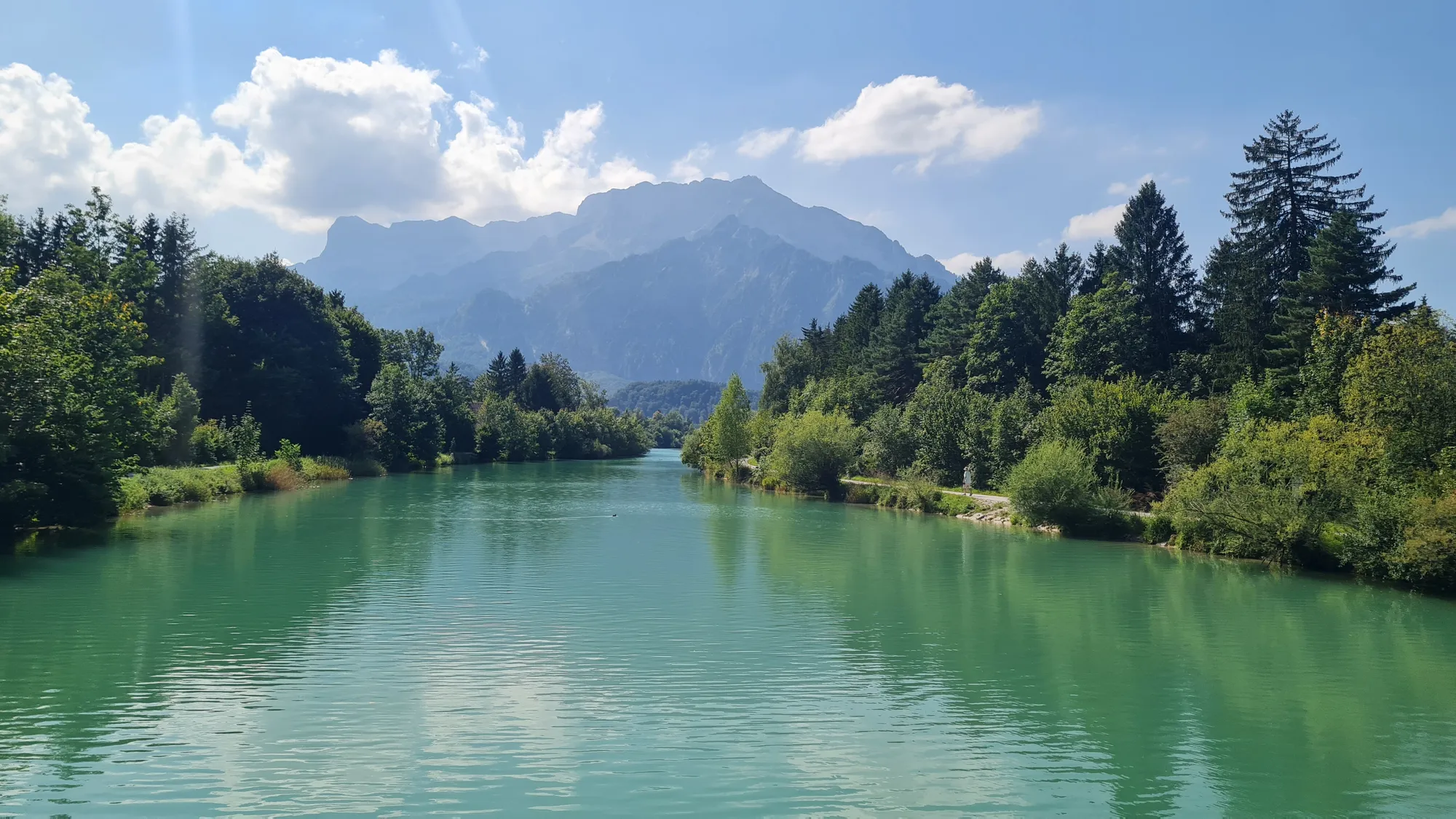 Turquoise river between forest, a mountain massif behind