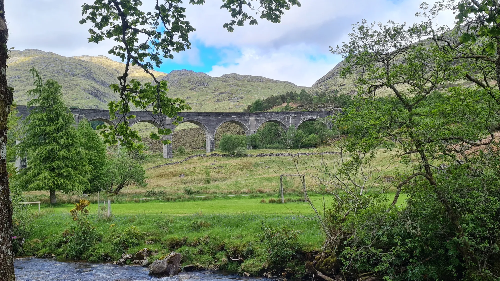 The Glenfinnan Viaduct behind trees and a stream
