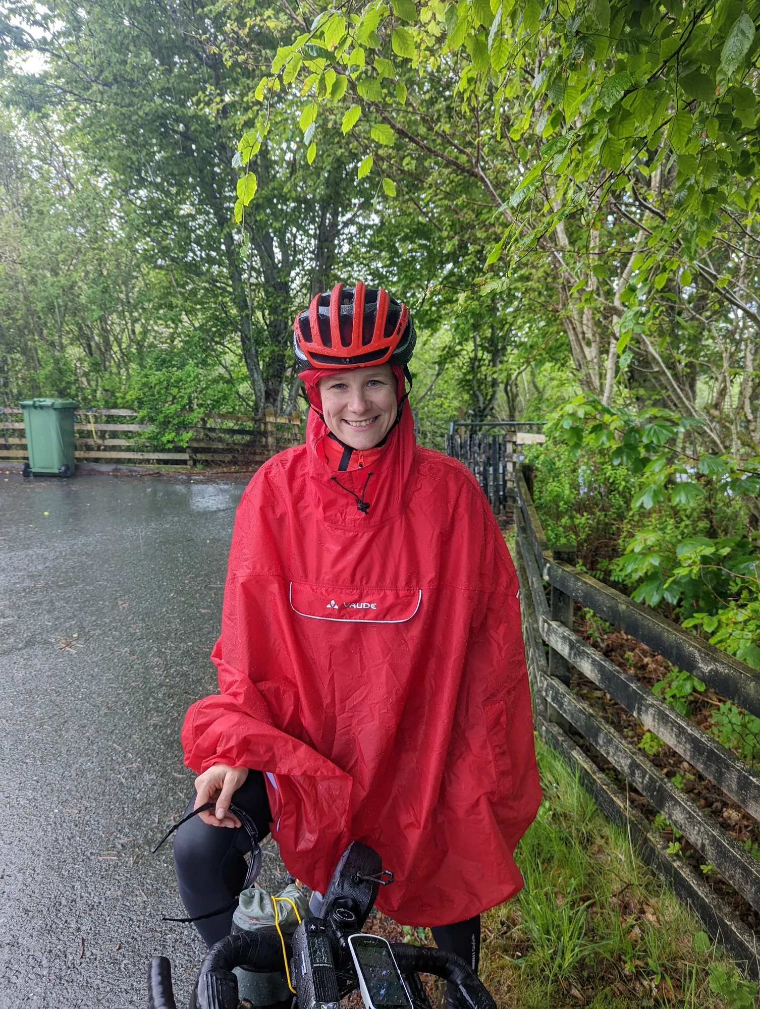 Carla in a red rain cape with a wet helmet