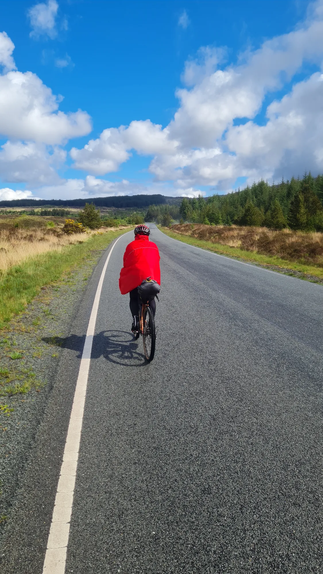 In the red rain cape on an empty road under a blue sky