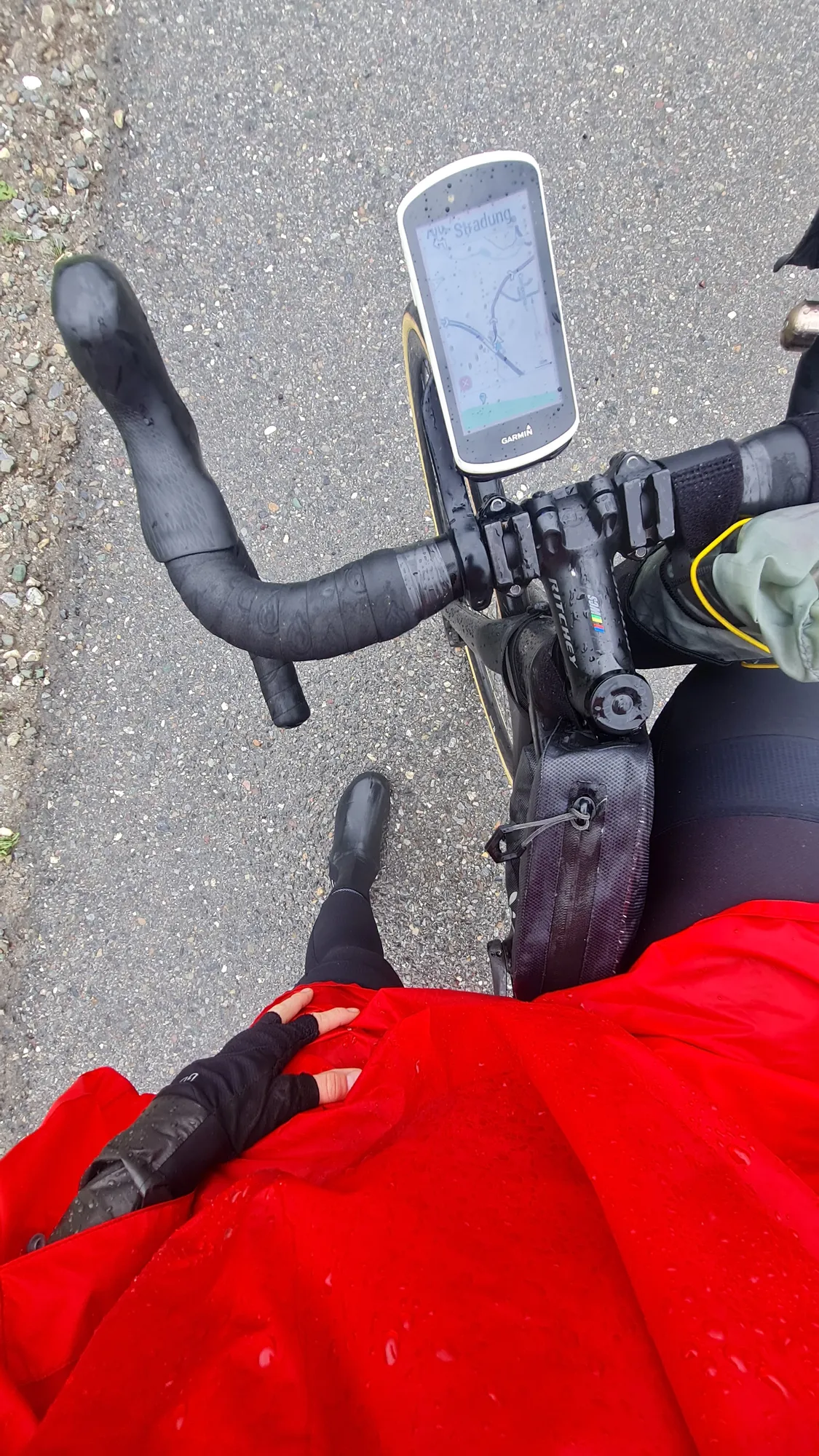 Red rain poncho and wet handlebars with bike computer
